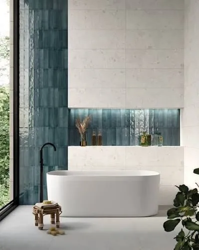 Freestanding bath beside blue and white ceramic wall tiles